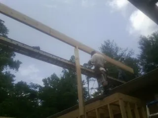 Carpenter setting a ridge beam over a new addition frame — Ice Dam Removal by Roofing Brothers in Valley Stream