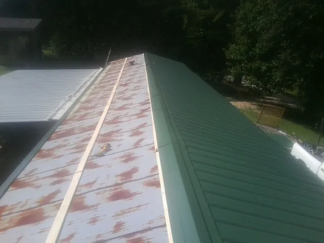 Old rusted panels beside newly installed green metal roofing — Wind Damage Roof Repair by Roofing Brothers in Valley Stream