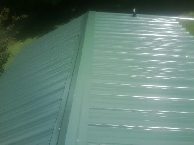 New green metal panels meeting at the ridge of a roof — Flat Roof Repair work by our crew in Valley Stream