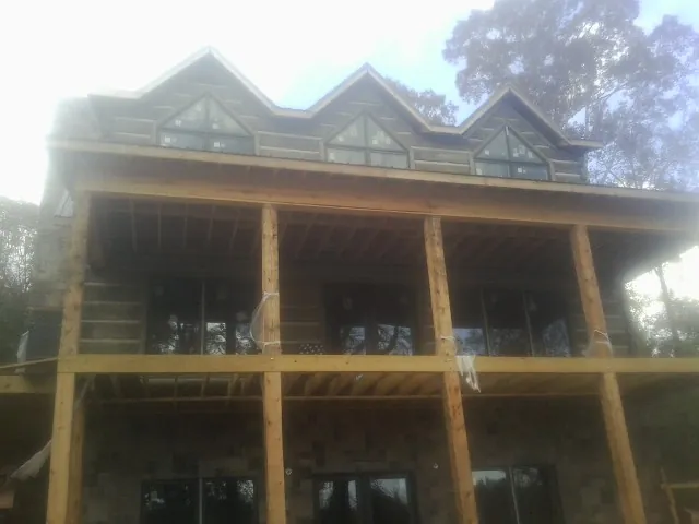 Dormers and porch framing on a large log home under construction — Roof Coating work by our crew in Valley Stream