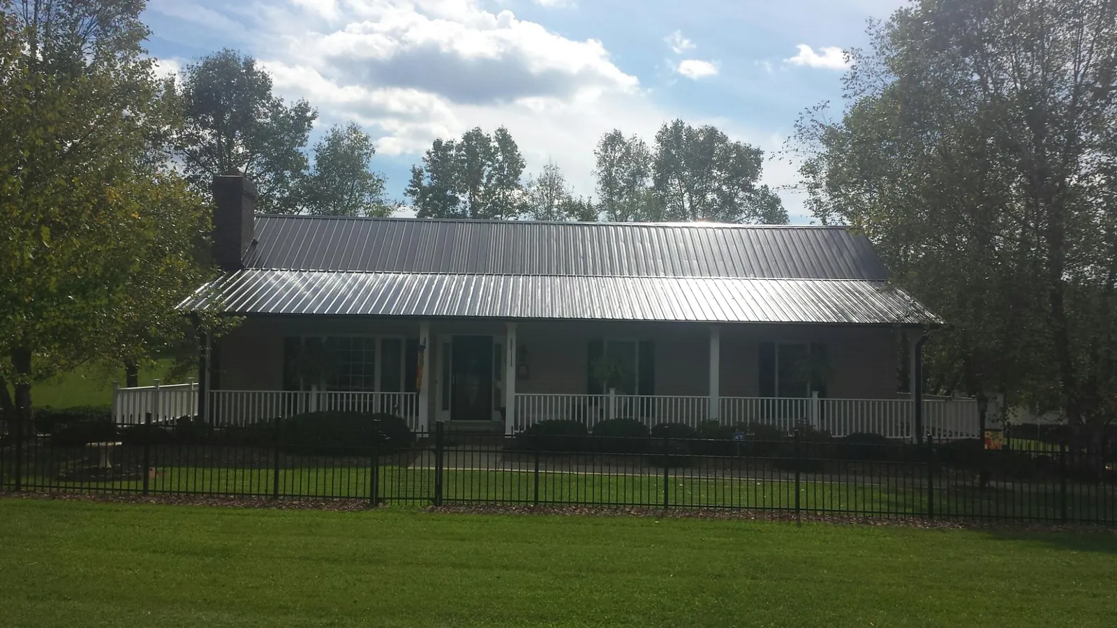 Gray metal roof on a brick ranch with a full width front porch — Gutter Guard Installation work by our crew in Valley Stream