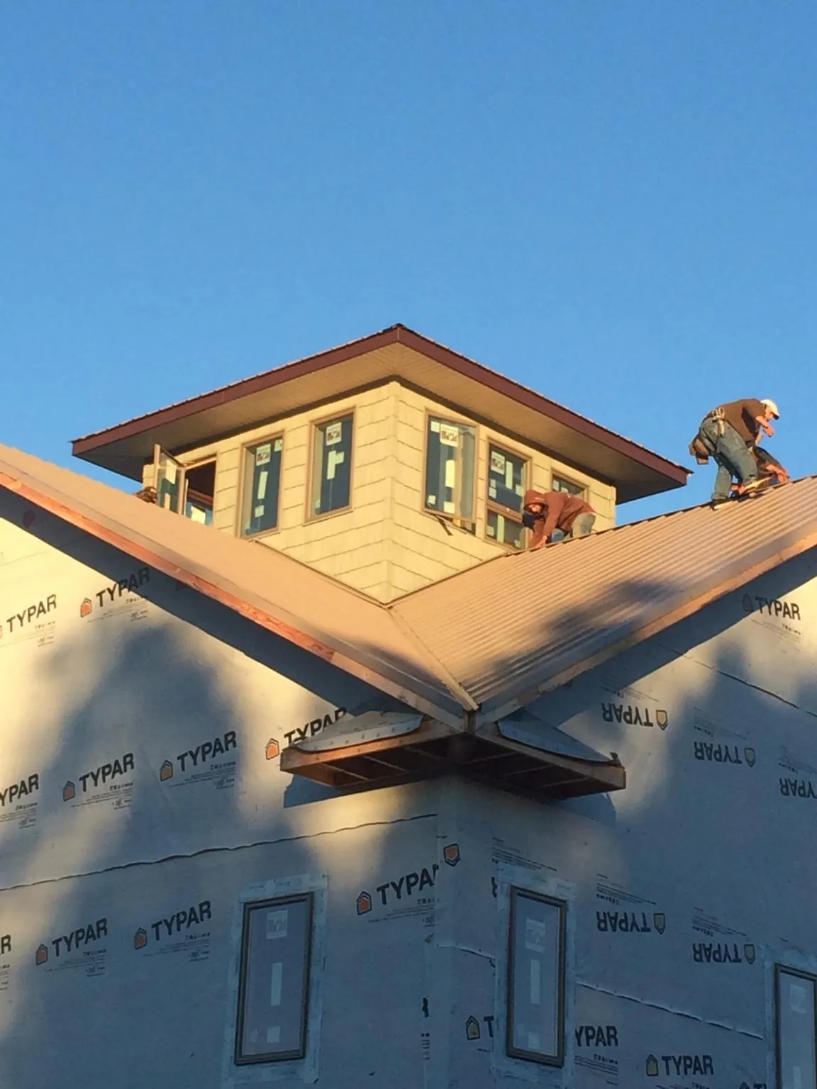 Roofers working around a rooftop cupola on a new metal roof at sunset — Roof Waterproofing in Valley Stream by Roofing Brothers